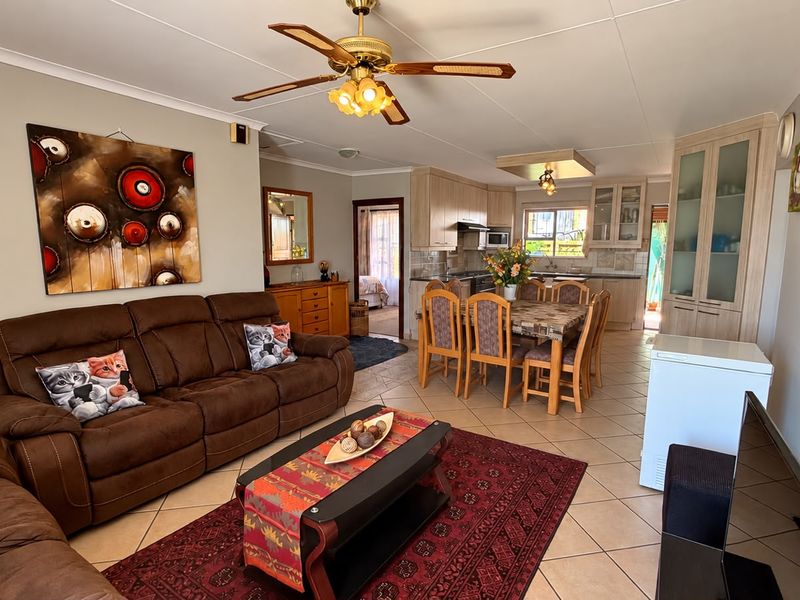 Spacious open-plan living and dining area featuring tiled flooring, a ceiling fan, and a functional kitchen with built-in cabinetry and appliances.