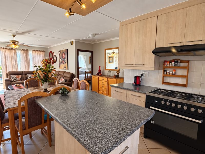 Open-plan living and dining area featuring a functional kitchen with laminate cabinetry, gas stove, and a central island, flowing into the lounge space.