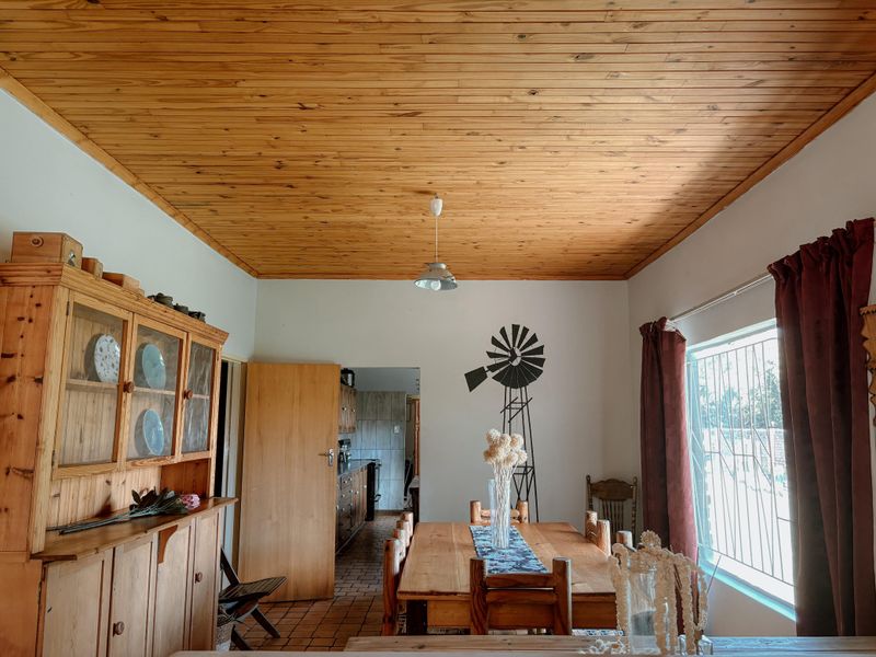 Dining area featuring a timber-clad ceiling, tiled flooring, and a view through to the kitchen area.