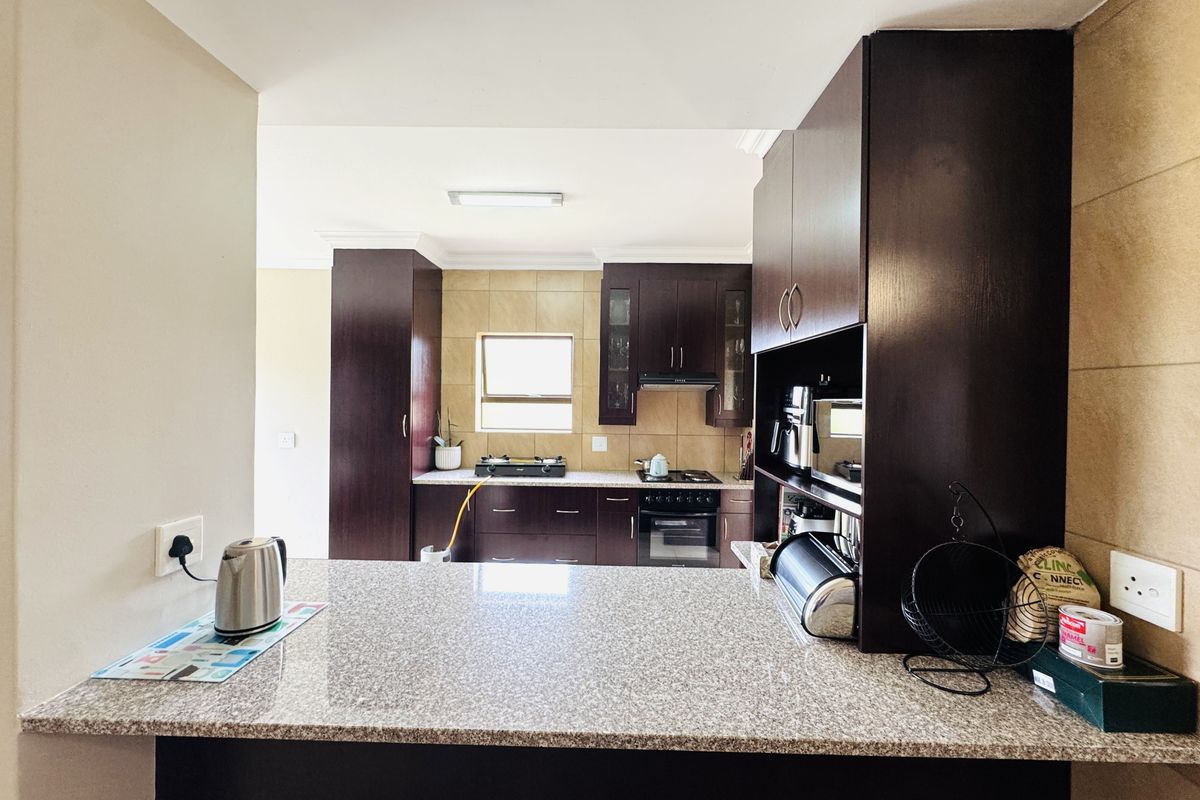 A functional kitchen featuring dark wood cabinetry, granite countertops, a breakfast bar, and built-in cooking appliances with a tiled backsplash.