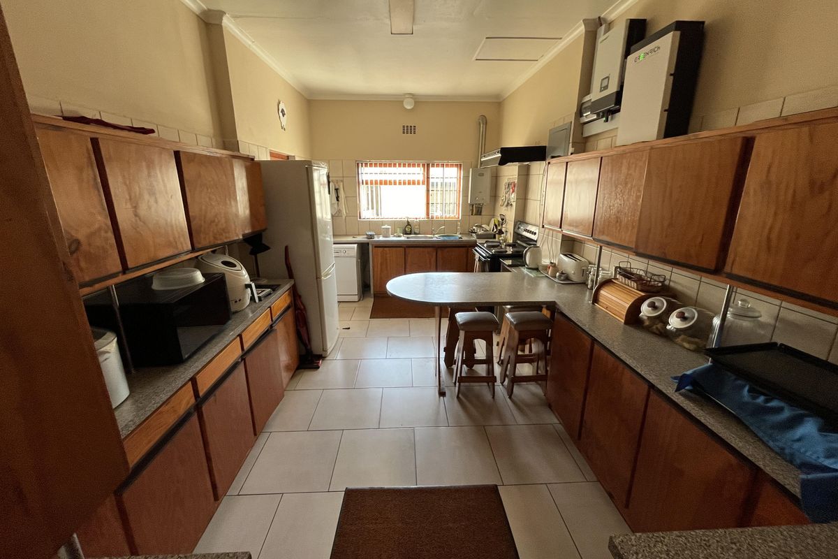A functional kitchen featuring wooden cabinetry, tiled flooring, a breakfast bar, and integrated appliances, offering a practical layout for daily meal preparation.