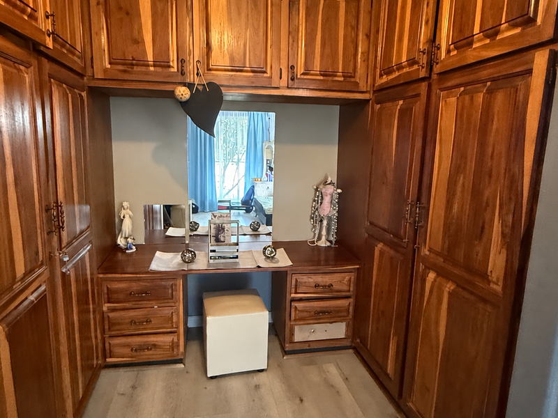 A bedroom featuring extensive built-in wooden cabinetry and a central vanity area with integrated mirror and storage drawers.