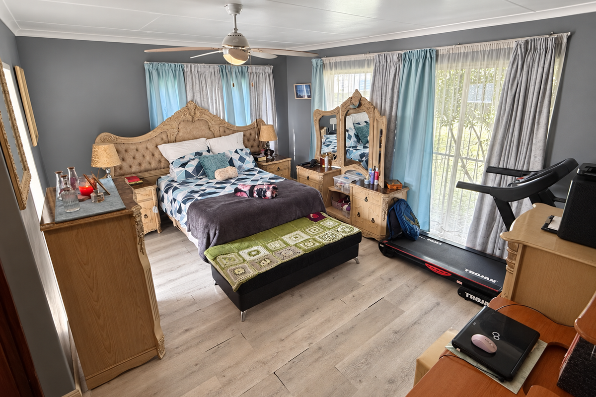 Spacious bedroom featuring light-toned laminate flooring, a ceiling fan, and large sliding glass doors that provide natural light and access to the exterior.
