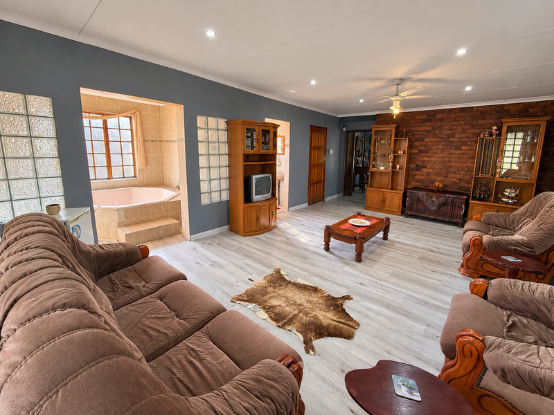 Spacious living room featuring an exposed brick wall, recessed lighting, and a unique integrated corner bathtub area with glass block accents.