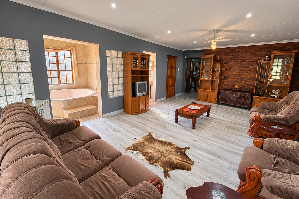 Spacious living room featuring an exposed brick wall, recessed lighting, and a unique integrated corner bathtub area with glass block accents.
