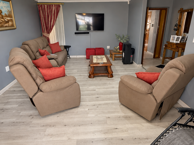 A well-maintained living room featuring modern laminate flooring, recessed ceiling lighting, and a central ceiling fan, creating a comfortable and functional living space.