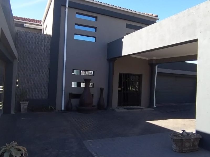 Modern front facade featuring a covered driveway, stone cladding accents, and a secure entrance area with contemporary architectural design.