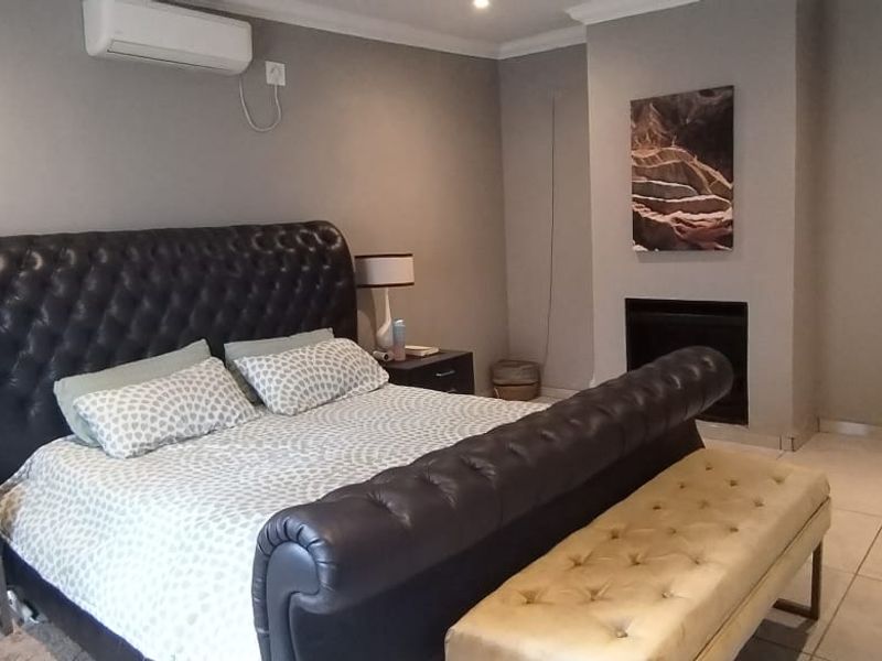 Spacious bedroom featuring tiled flooring, a built-in fireplace, and a wall-mounted air conditioning unit, offering a comfortable and well-maintained living space.