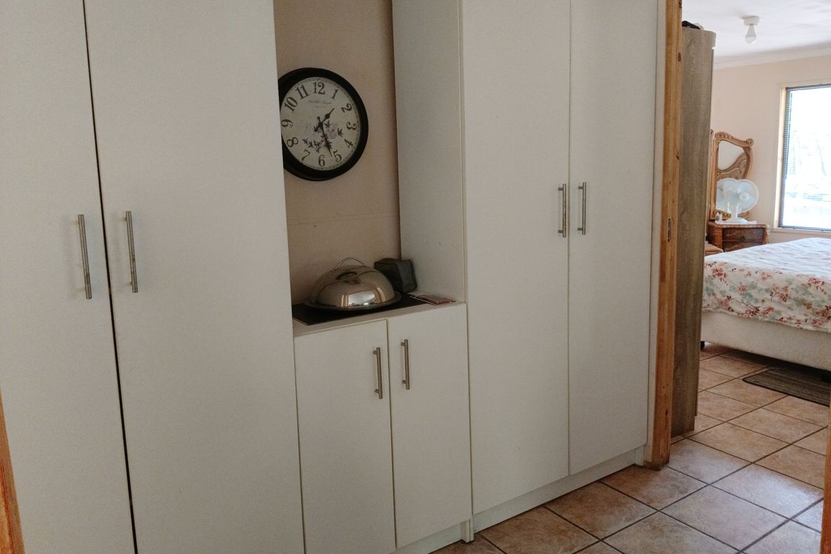 Bedroom featuring built-in white cabinetry with ample storage and ceramic floor tiles, leading into an adjacent sleeping area.