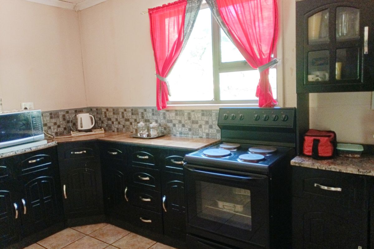 A functional kitchen featuring dark cabinetry, tiled backsplash, laminate countertops, and a freestanding stove with oven.