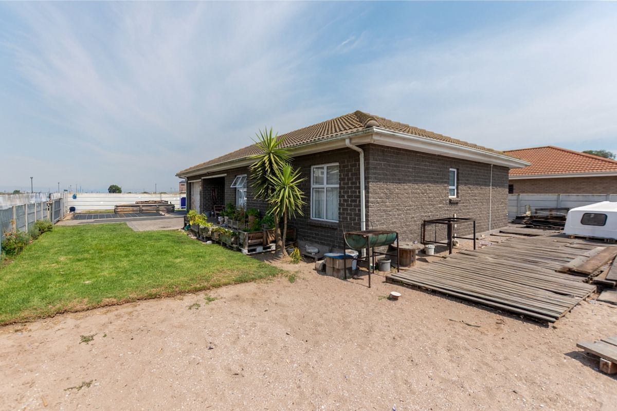 Rear view of a brick house featuring a tiled roof, small garden area, and wooden decking, offering potential for outdoor landscaping and improvement.