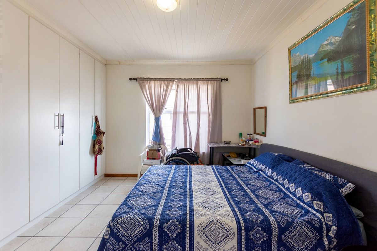 A bedroom featuring built-in floor-to-ceiling wardrobes, tiled flooring, and a tongue-and-groove ceiling finish.