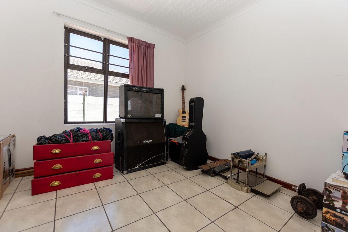 A bedroom featuring tiled flooring, an aluminium window with security bars, and a tongue and groove ceiling.