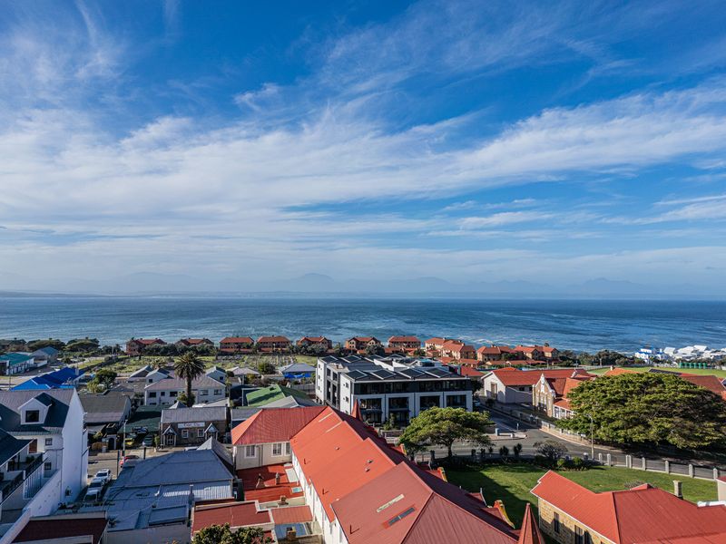An elevated aerial view showcasing the coastal neighborhood, surrounding residential properties, and the expansive ocean horizon.