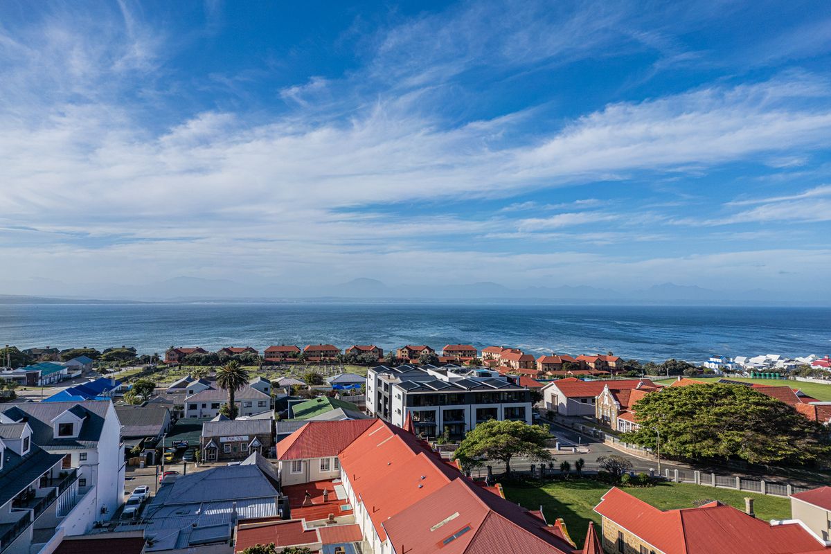 An elevated aerial view showcasing the coastal neighborhood, surrounding residential properties, and the expansive ocean horizon.
