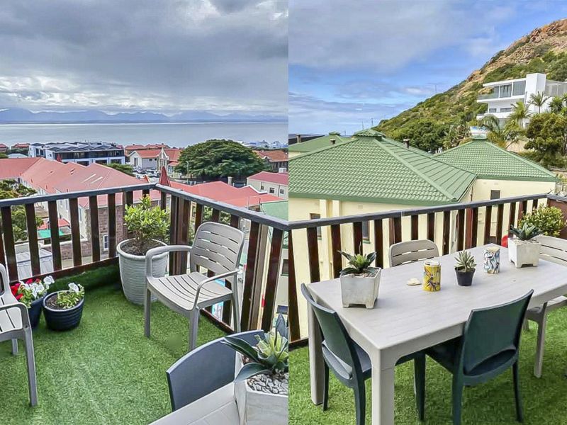 A balcony featuring artificial grass flooring and a railing, offering elevated views of the surrounding neighborhood and distant mountains.