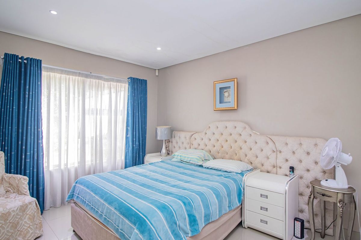 A well-maintained bedroom featuring neutral wall tones, tiled flooring, and recessed downlighting, providing a comfortable and functional living space.