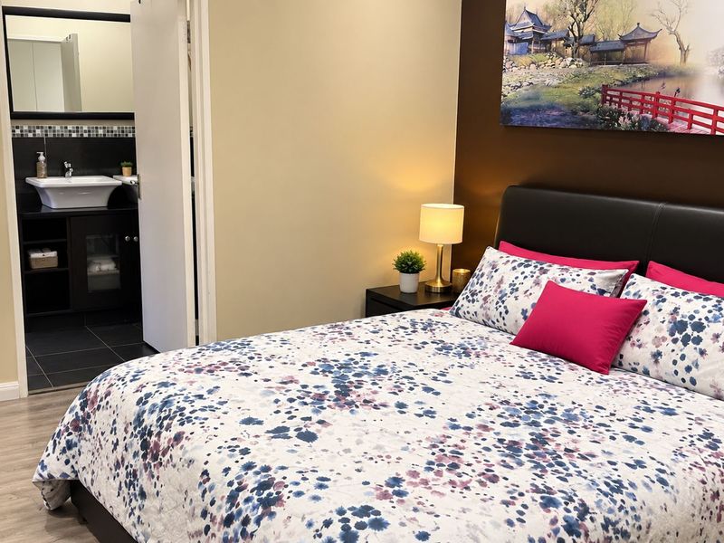 A well-maintained bedroom featuring laminate flooring and an adjoining en-suite bathroom with a modern vessel sink and vanity.