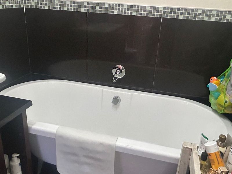 A bathroom featuring a modern freestanding bathtub with wall-mounted chrome fixtures and a decorative mosaic tile backsplash.