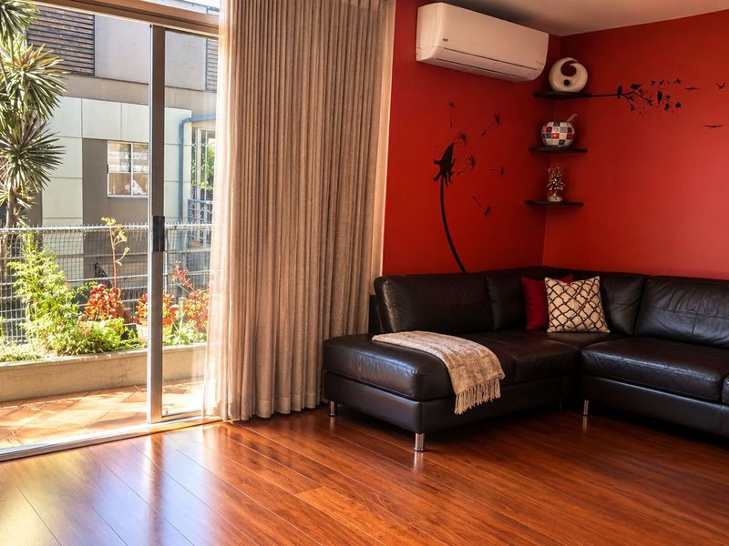 Living room featuring rich hardwood flooring, a split-system air conditioner, and large sliding glass doors providing access to an outdoor patio area.
