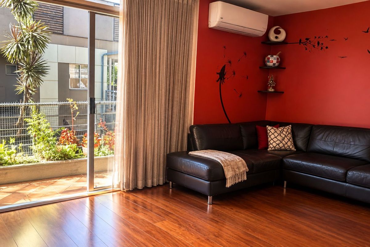 Living room featuring rich hardwood flooring, a split-system air conditioner, and large sliding glass doors providing access to an outdoor patio area.