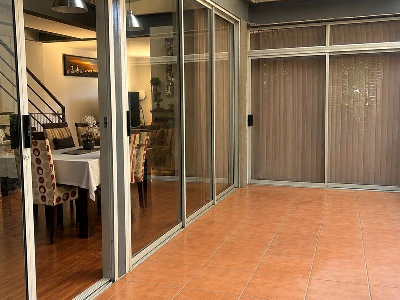 A covered patio area featuring tiled flooring and large sliding glass doors providing seamless access to the interior living and dining spaces.