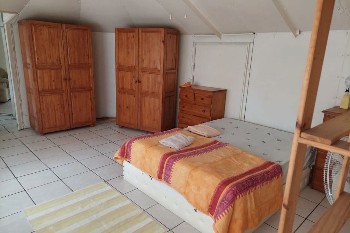 A bedroom featuring tiled flooring and a pitched ceiling with visible paneling, offering a functional space with potential for cosmetic updates.