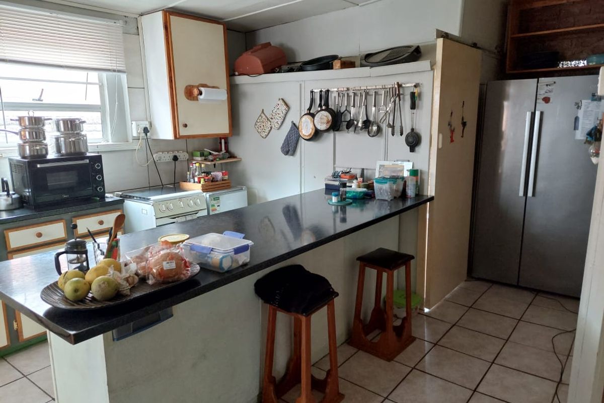 Functional kitchen featuring a breakfast bar, tiled flooring, and ample cabinetry, offering potential for modernization and aesthetic updates.
