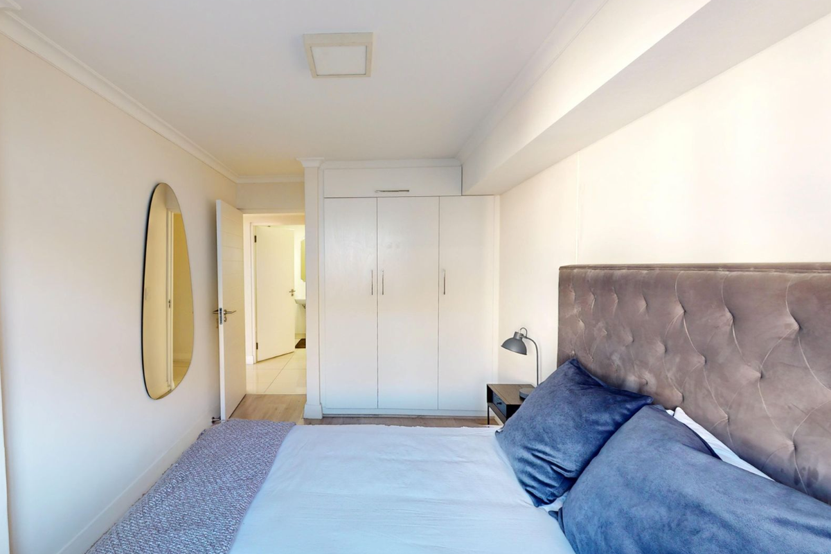 A well-maintained bedroom featuring built-in wardrobes, neutral finishes, and direct access to an adjoining bathroom.