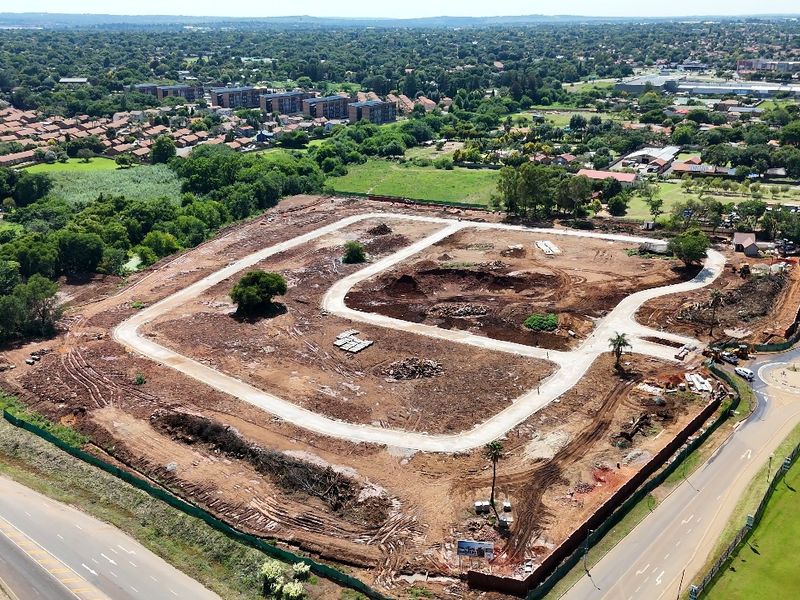 Aerial view of a residential development site featuring cleared plots and newly constructed internal paved roads in a suburban setting.