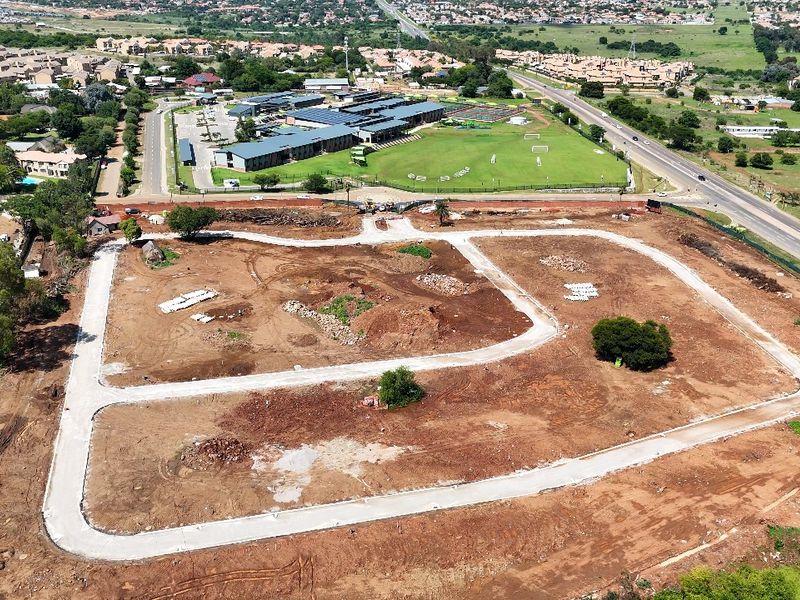 Aerial view of a residential development site featuring cleared land, established internal road infrastructure, and proximity to local amenities and main roads.