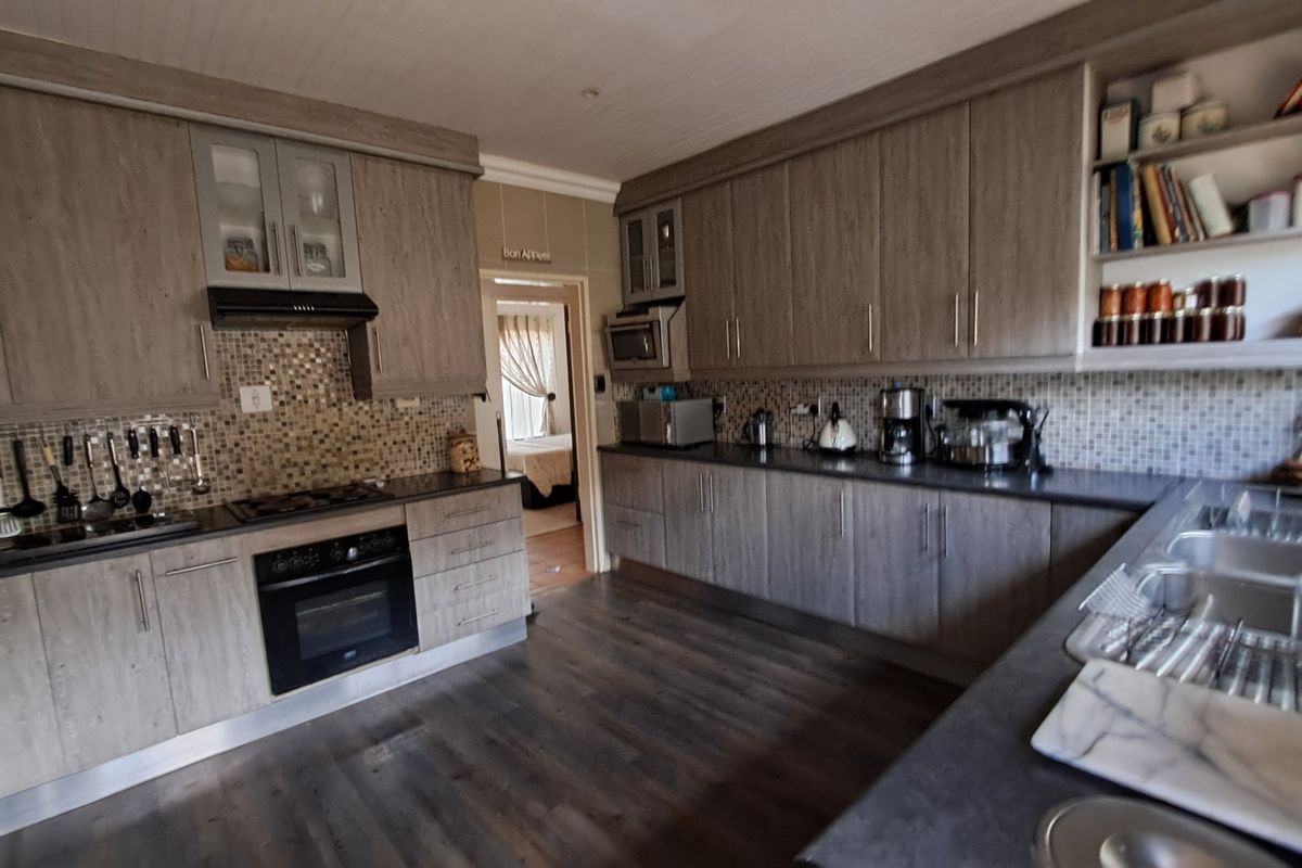A functional kitchen featuring wood-grain cabinetry, mosaic tile backsplash, built-in oven, gas hob, and ample counter space with a double sink.