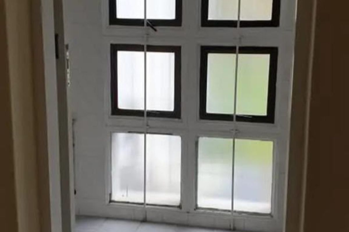 A vacant bathroom space featuring tiled flooring and a large grid-pattern window configuration, awaiting modernization and fixture installation.
