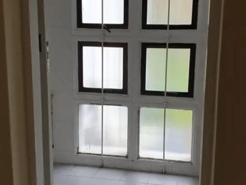 A vacant bathroom space featuring tiled flooring and a large grid-pattern window configuration, awaiting modernization and fixture installation.