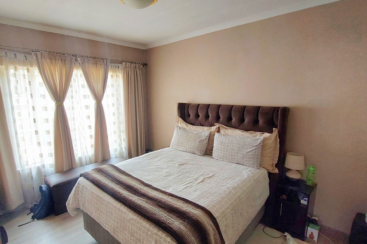 A well-lit bedroom featuring laminate flooring and neutral wall tones, providing a comfortable and functional sleeping space.