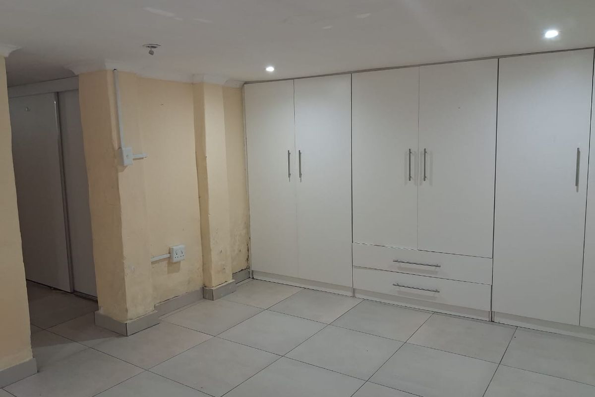 A bedroom featuring built-in white cabinetry, tiled flooring, and recessed ceiling lighting.