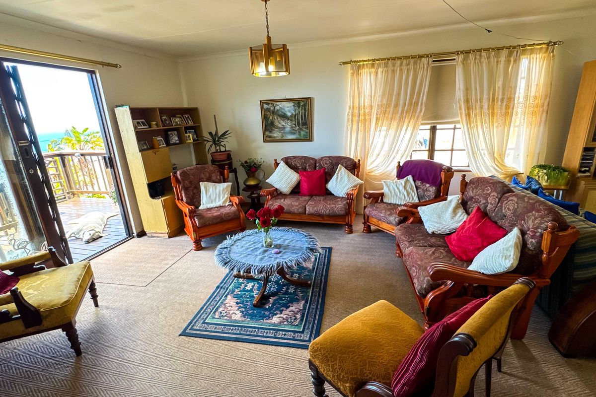 Spacious living room featuring carpeted flooring and a large sliding glass door providing access to an outdoor balcony with ocean views.