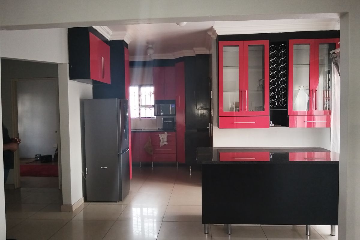 A kitchen featuring high-contrast red and black cabinetry, a central island, and tiled flooring, offering a modern layout with integrated storage solutions.
