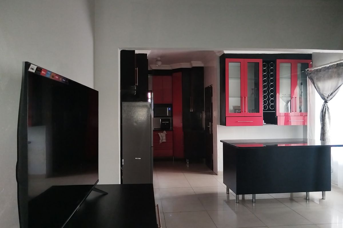 Open plan living area featuring a kitchen with bold red and black cabinetry, a central island, and tiled flooring throughout.