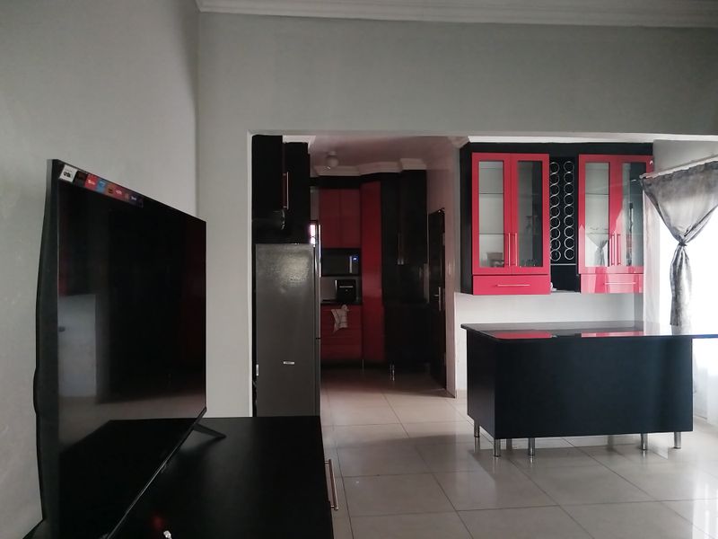 Open plan living area featuring a kitchen with bold red and black cabinetry, a central island, and tiled flooring throughout.