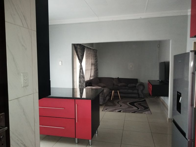 Open plan living area featuring a kitchen island with granite countertops and tiled flooring, seamlessly connecting to the adjacent lounge space.