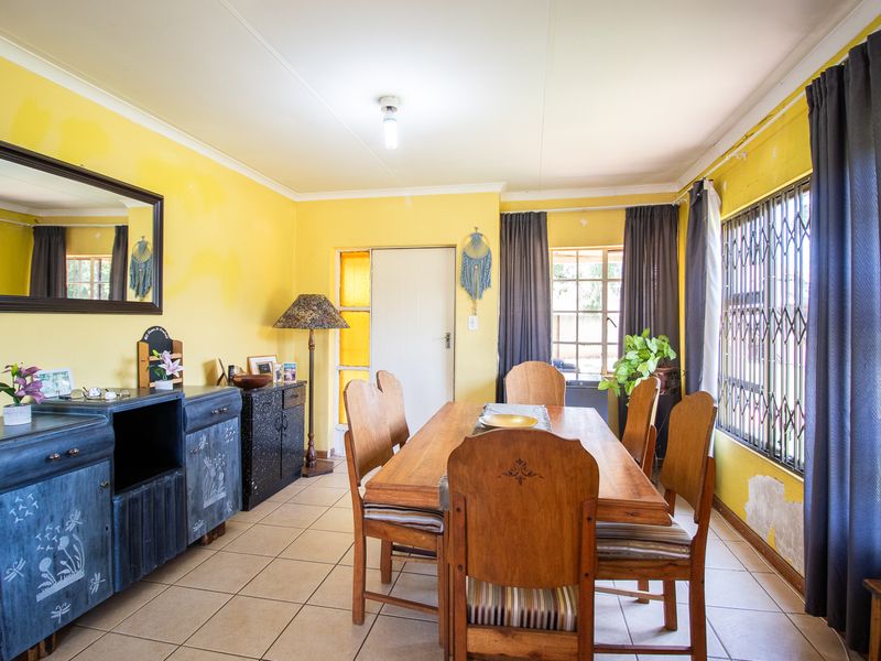 Dining room featuring tiled flooring and security gate, currently requiring cosmetic updates to the wall finishes.
