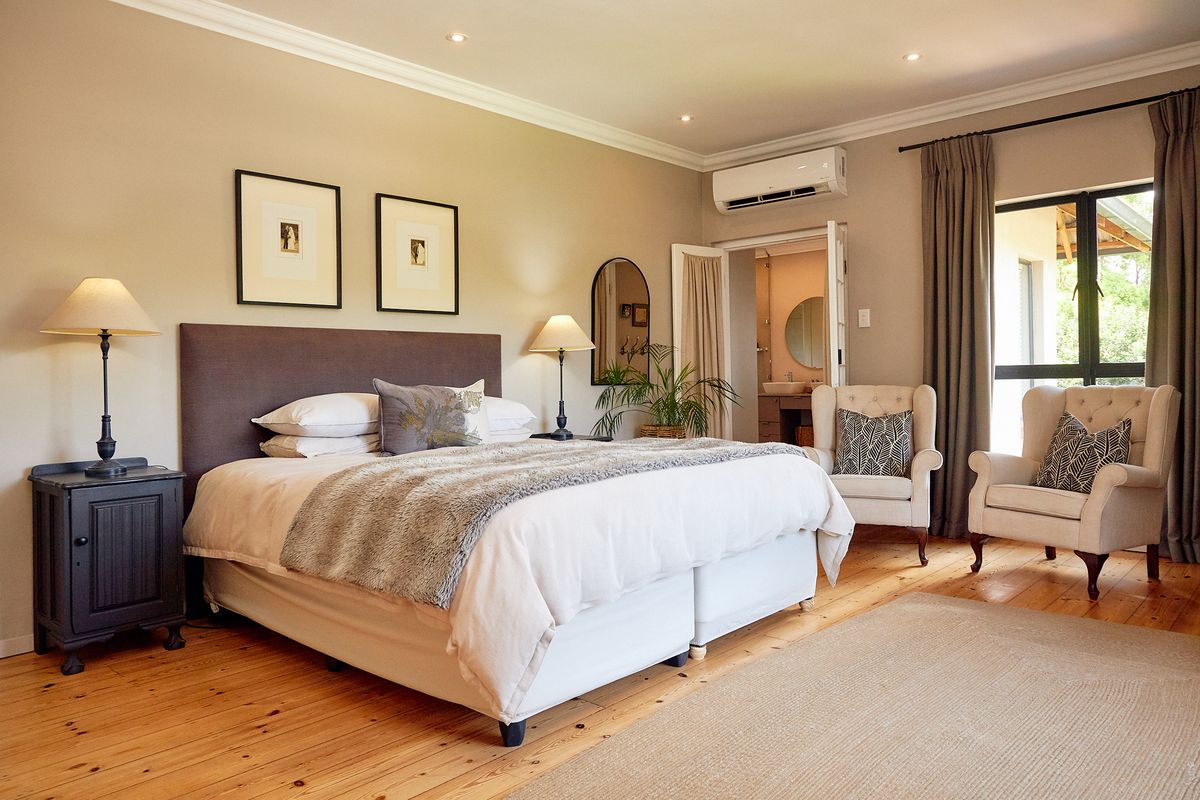 Spacious bedroom featuring polished timber flooring, recessed downlighting, a split-system air conditioner, and direct access to an en-suite bathroom.