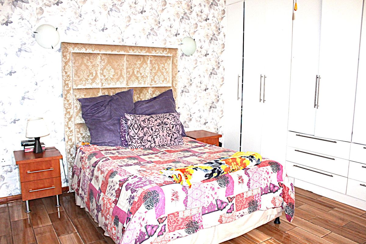 A bedroom featuring built-in wardrobes, tiled flooring, and wall-mounted lighting fixtures.