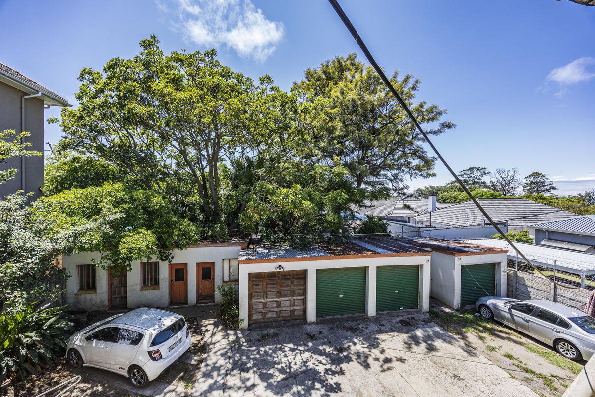 An elevated view of the property's rear exterior, featuring multiple garage bays, a concrete driveway, and mature trees surrounding the building structure.