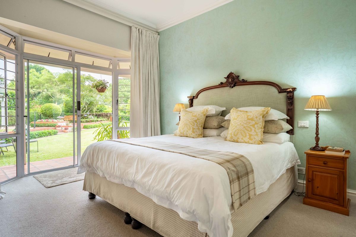 A well-maintained bedroom featuring carpeted flooring, decorative coving, and large sliding glass doors providing direct access to the garden.