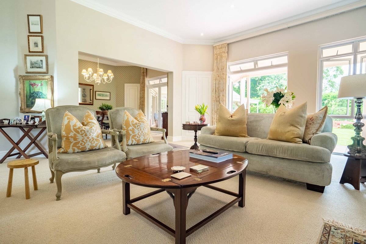 A bright and spacious living room featuring crown molding, recessed lighting, and large windows that provide ample natural light and garden views.