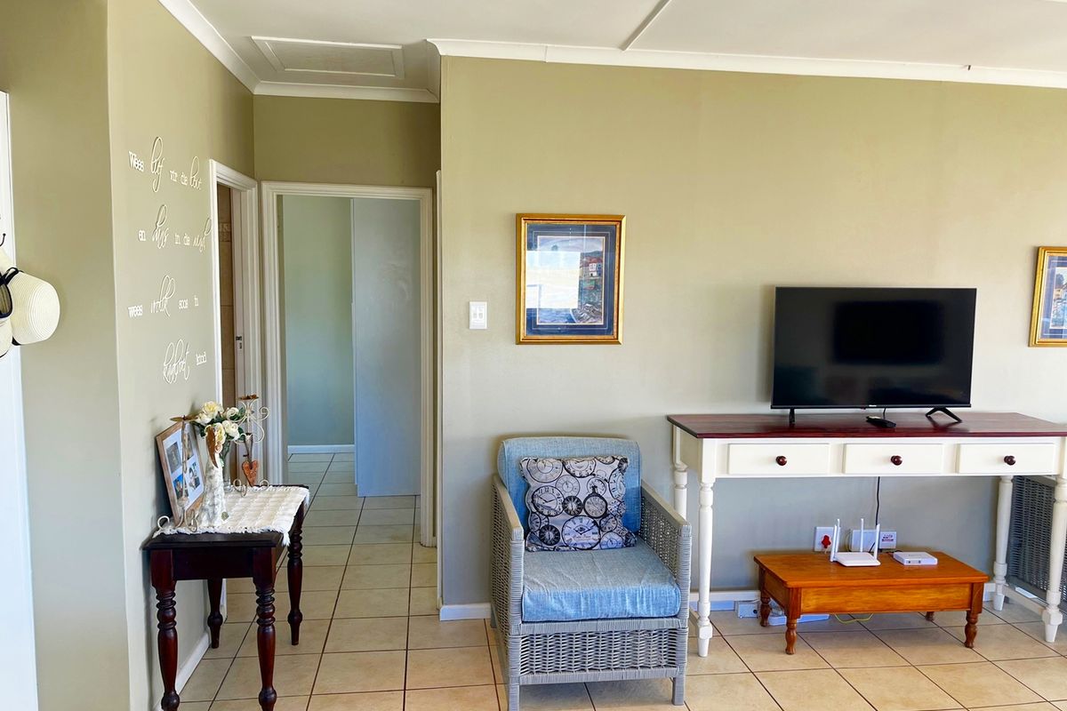 A living room area featuring ceramic floor tiles and coved ceilings, providing access to adjacent rooms through internal doorways.