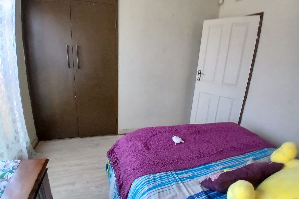 A functional bedroom featuring laminate flooring and a built-in wardrobe, providing essential storage space.