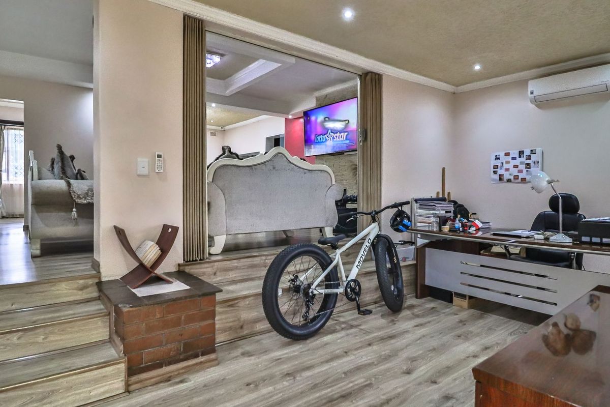 A multi-level living area featuring laminate flooring, recessed lighting, and a split-system air conditioner, with a step-up transition to an adjacent lounge space.